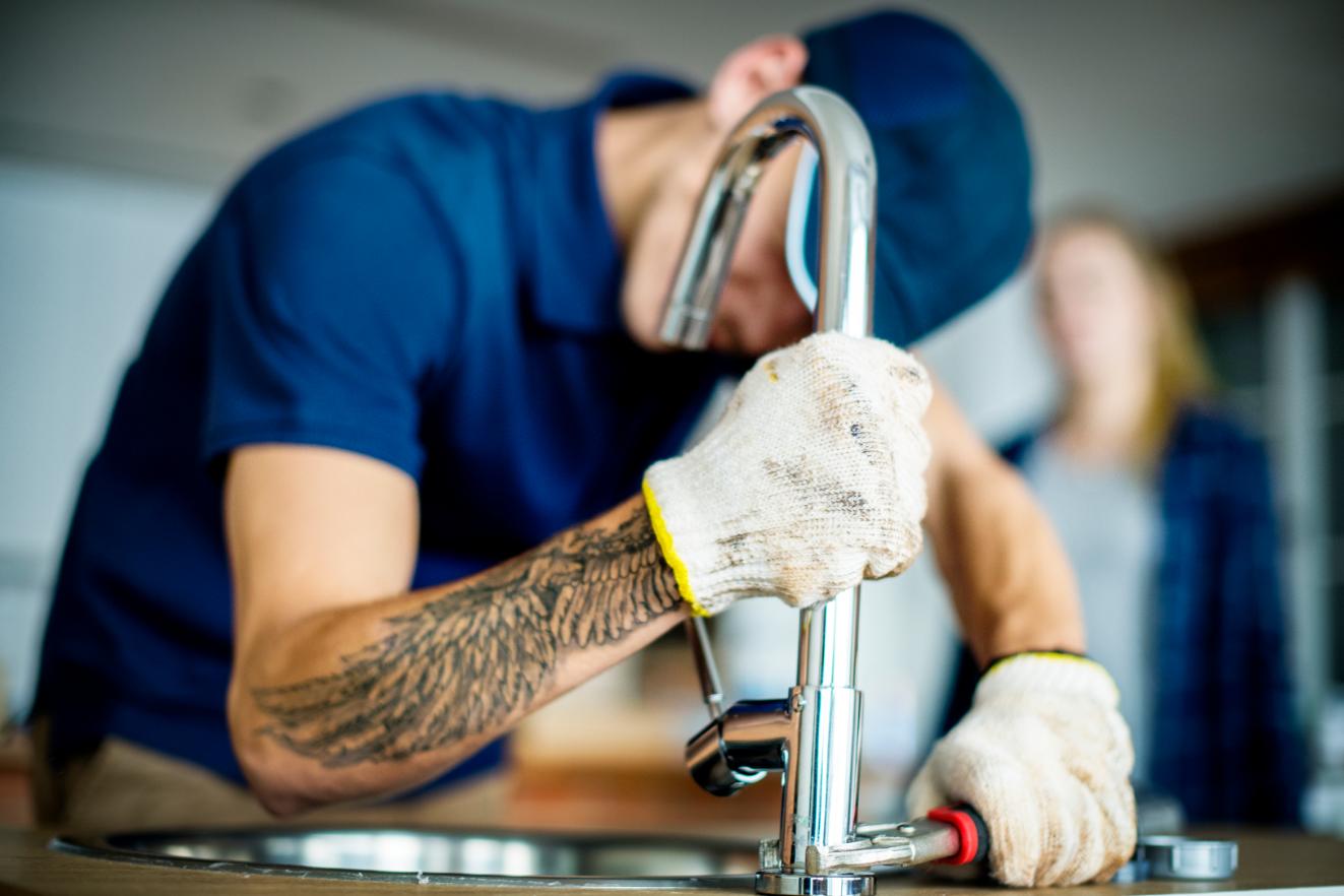 Professional plumber fixing kitchen sink with precision tools